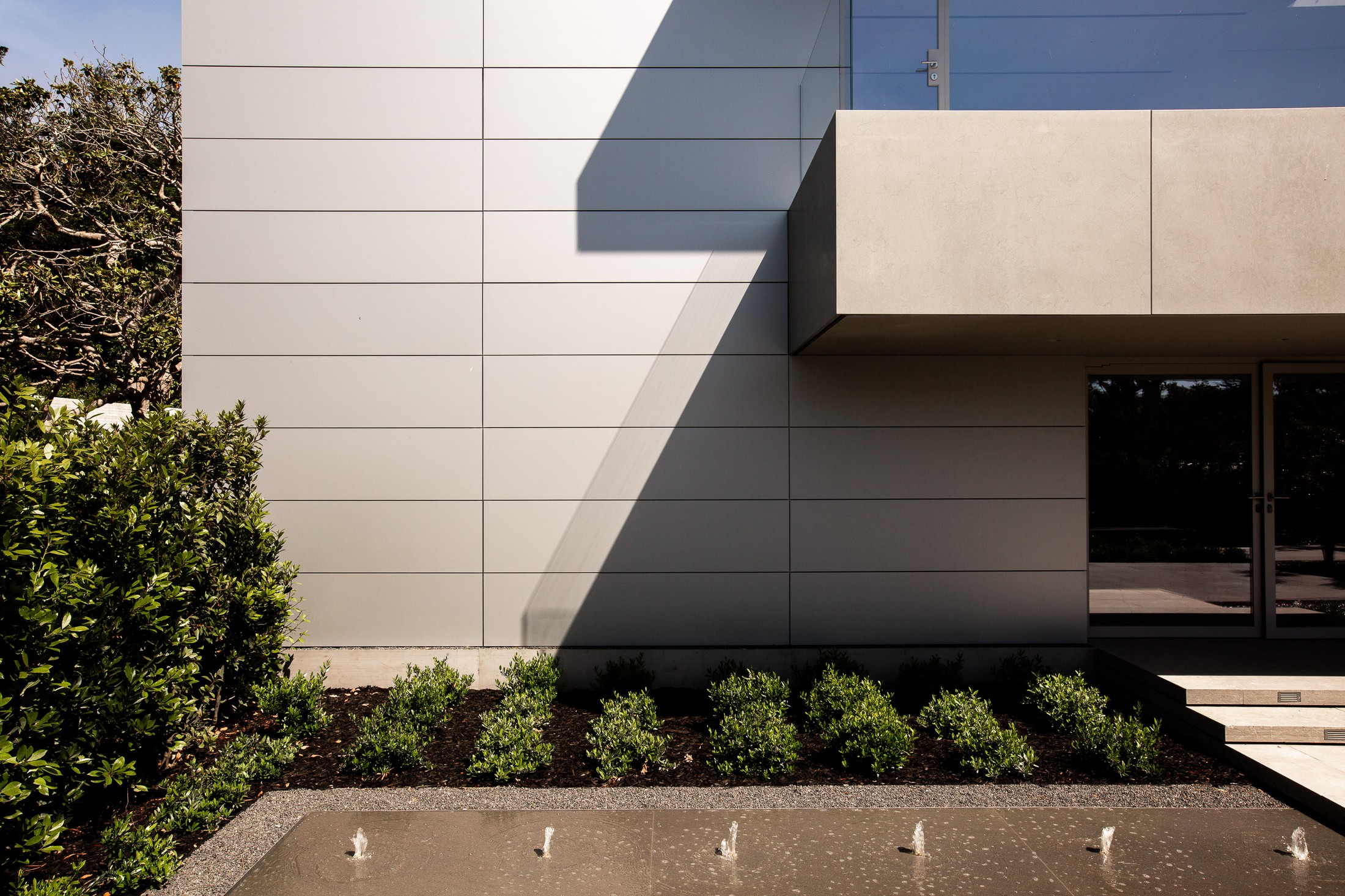Detailed image of the exterior of the home, with a small fountain and trees