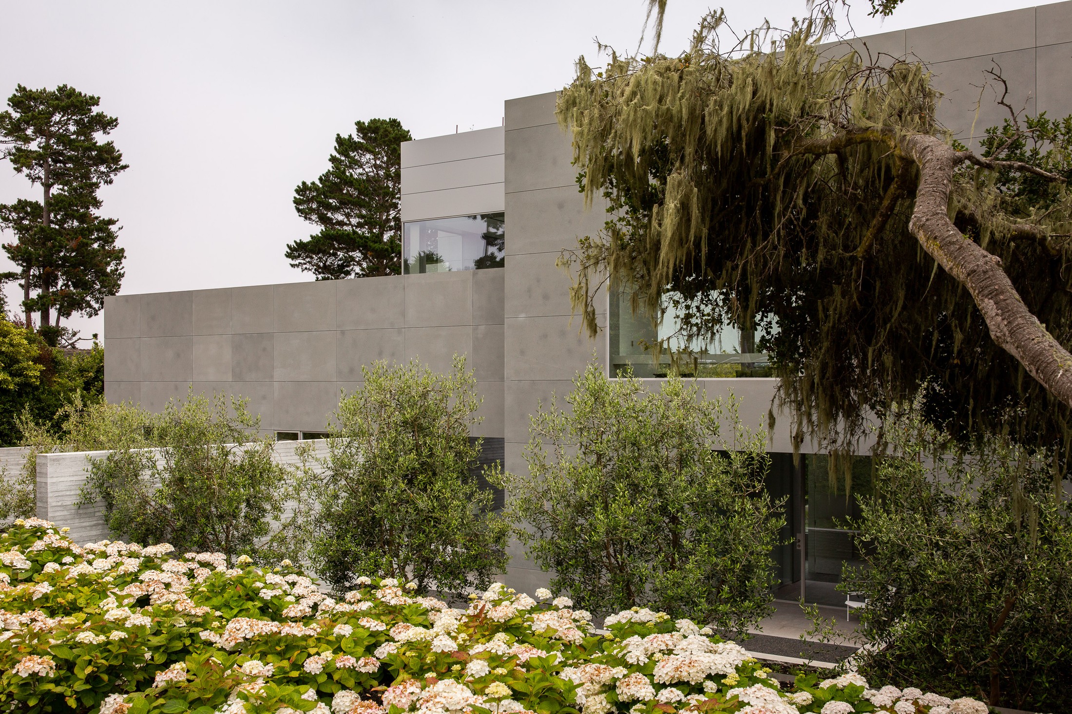 Exterior image of the home, which includes flowers and trees.