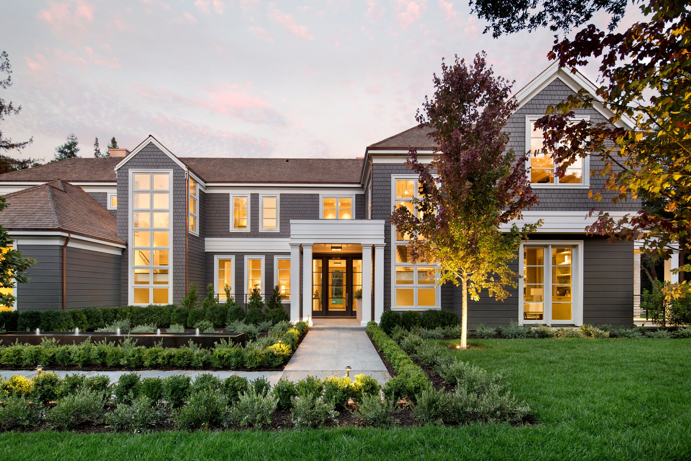 Entryway to the home with plant and tree lined walkway