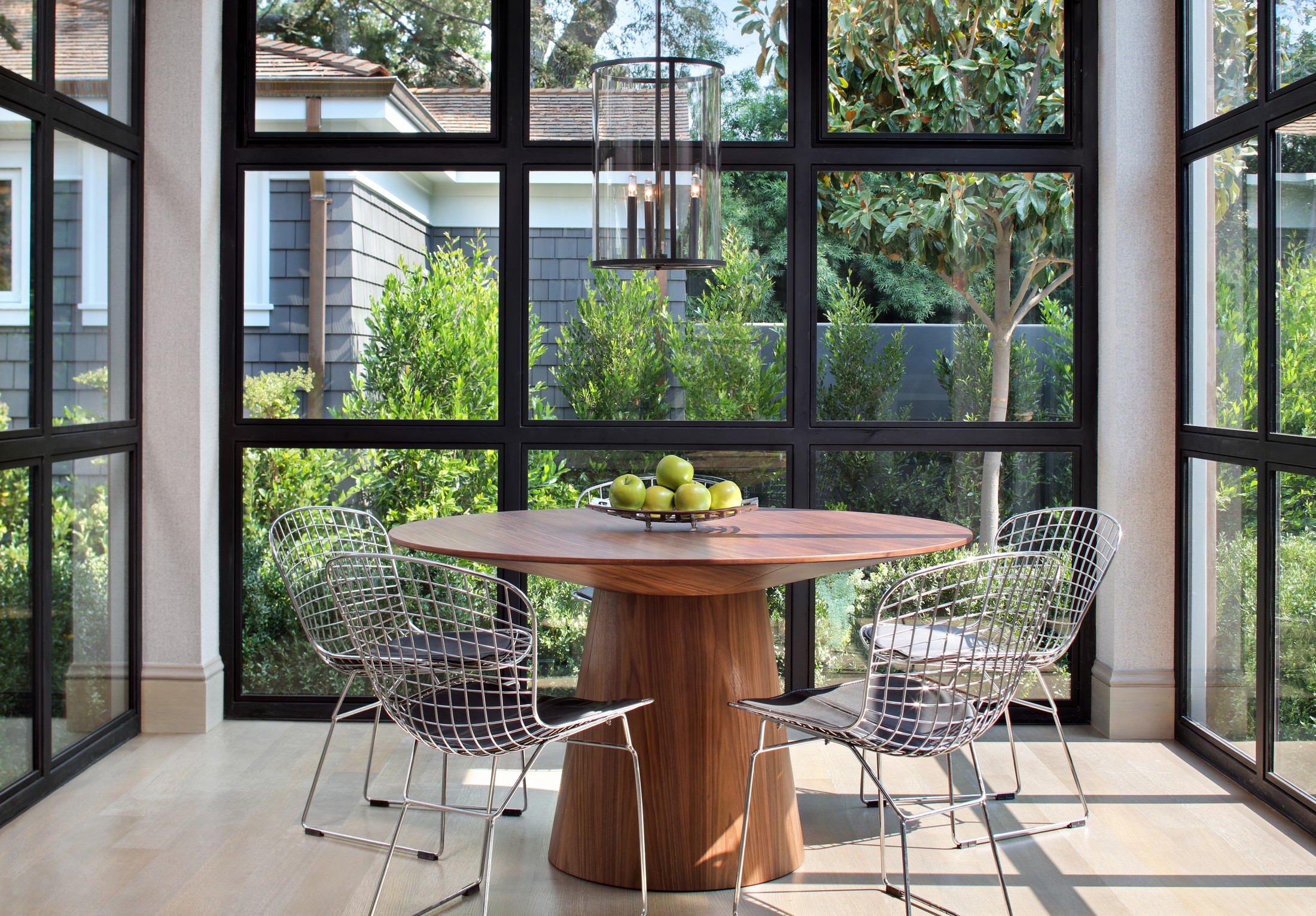 Kitchen seating with silver netted chairs and a wooden table.
