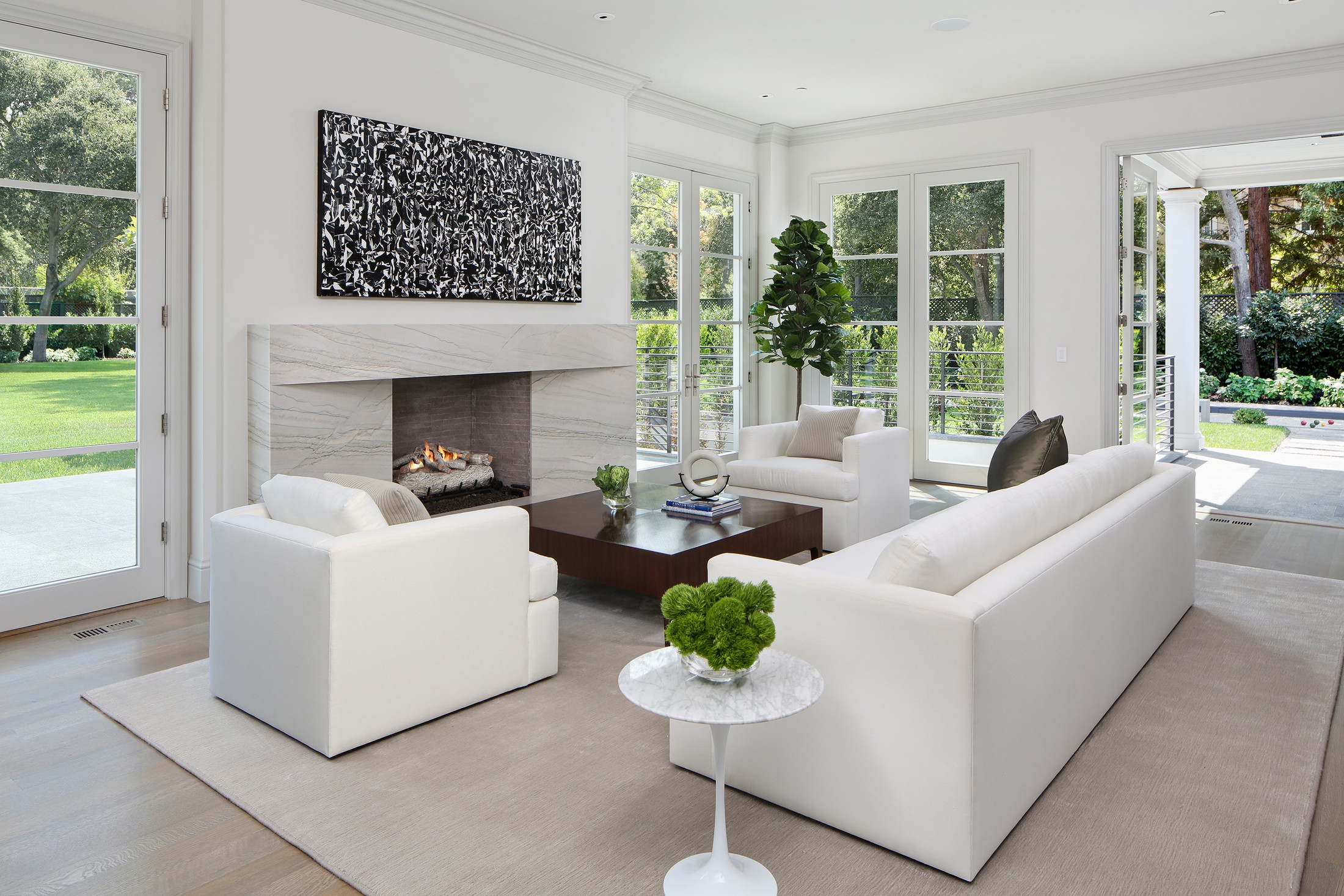 Seating area with white furniture, and a marble fireplace.