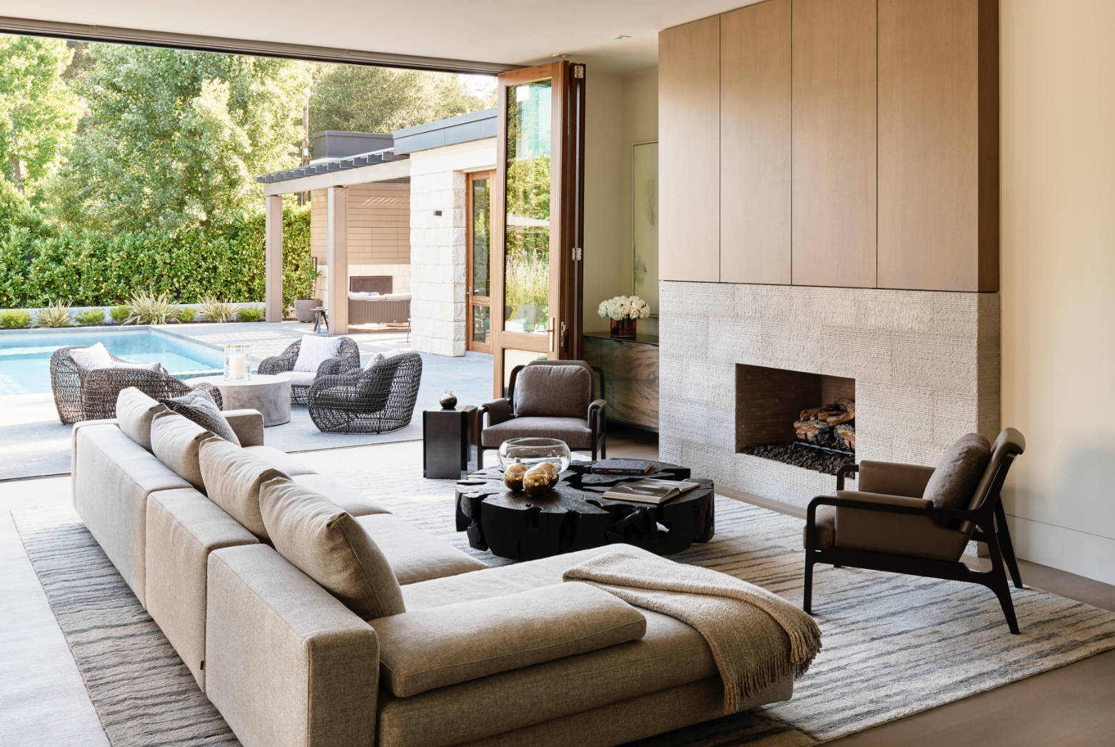 Pool house living room, which a large sofa, fireplace, and black table in the center of the room.