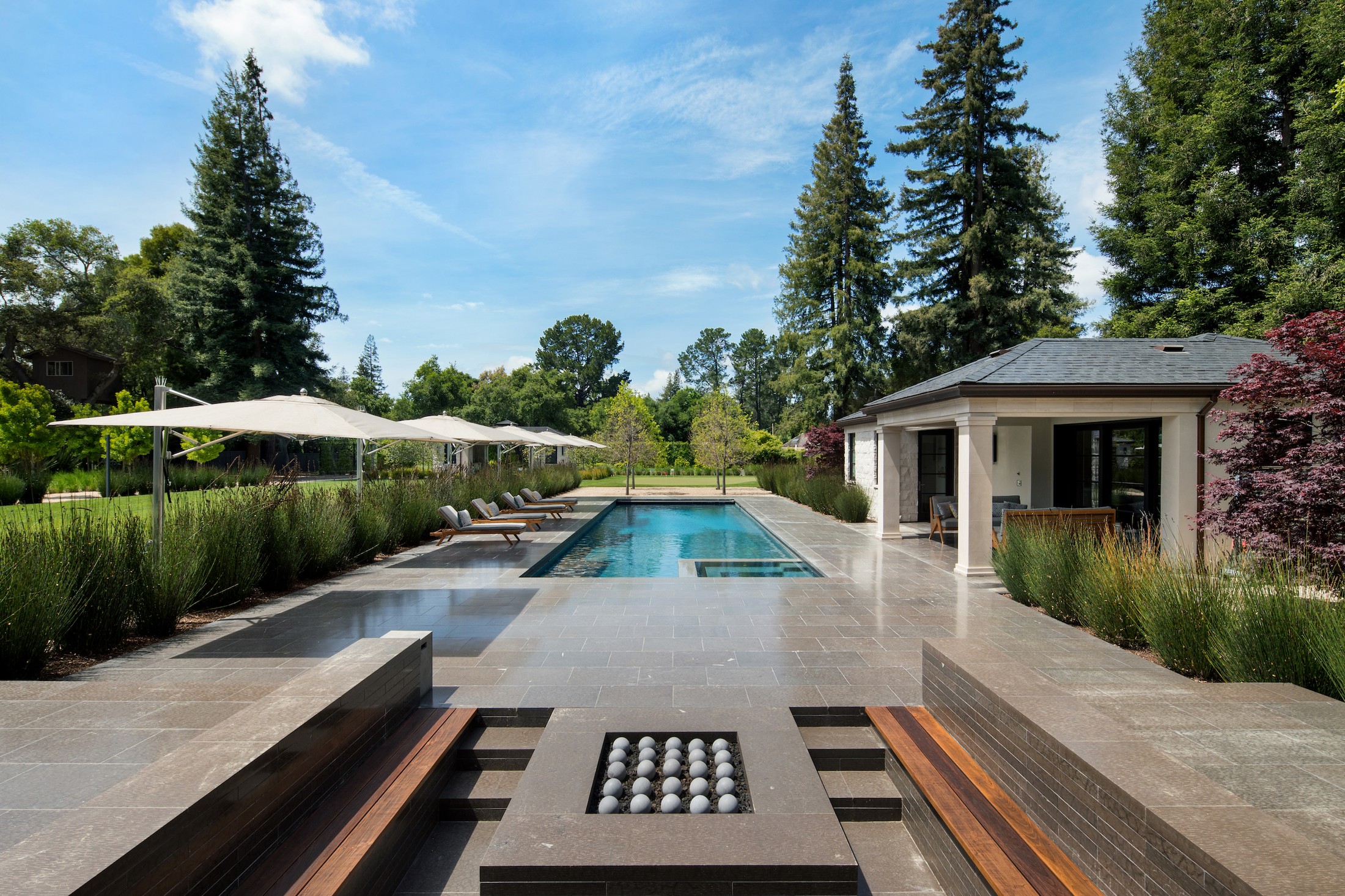 Back exterior image which includes a fireplace, hot tub, and pool with a pool house.