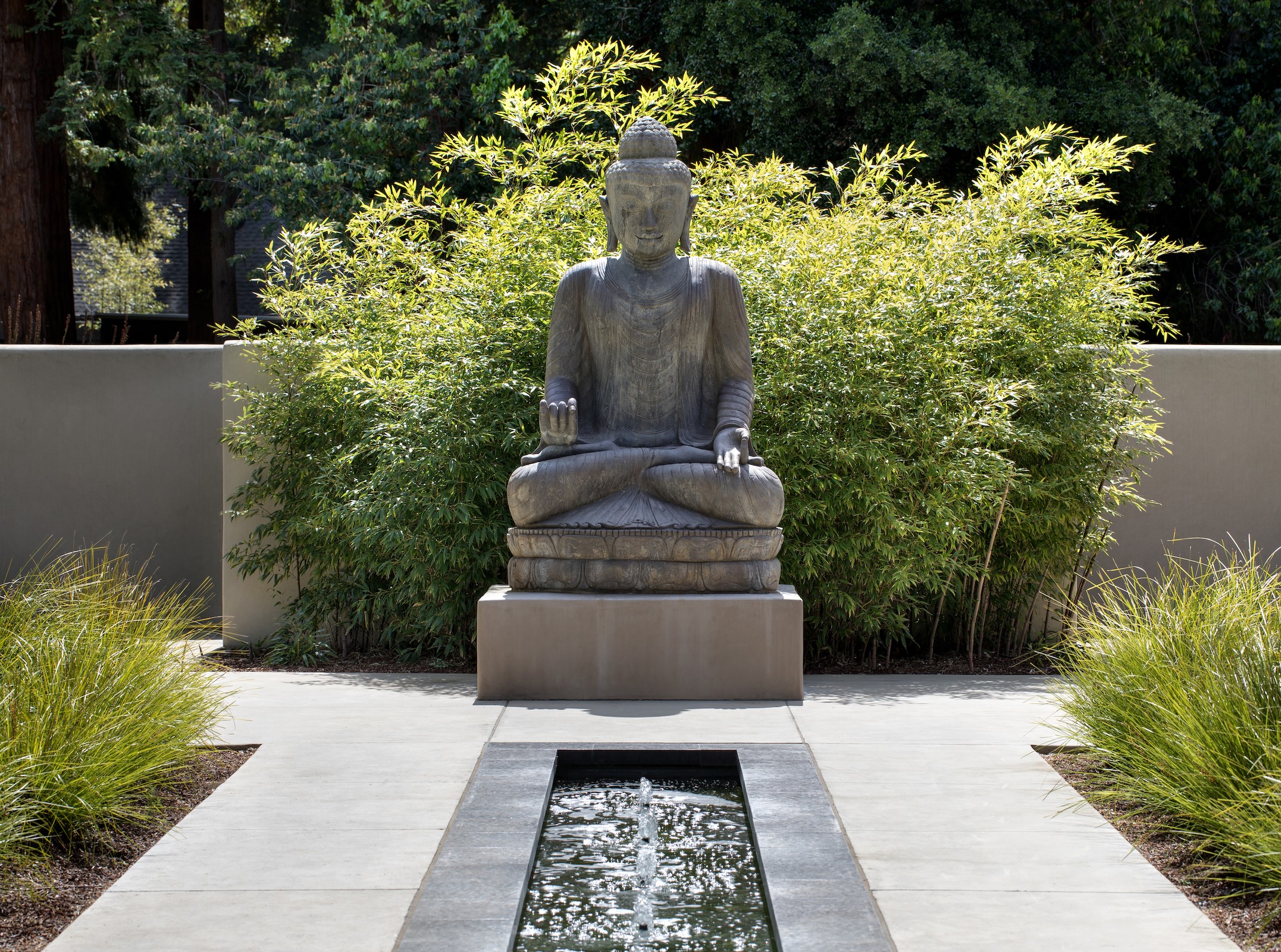 Buddha sculpture in front of a fountain outside