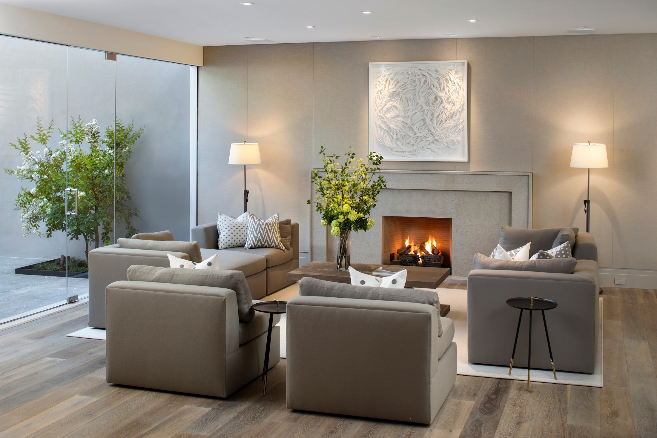 Seating area with a fireplace, large white artwork, and furniture which includes a sofa and chairs