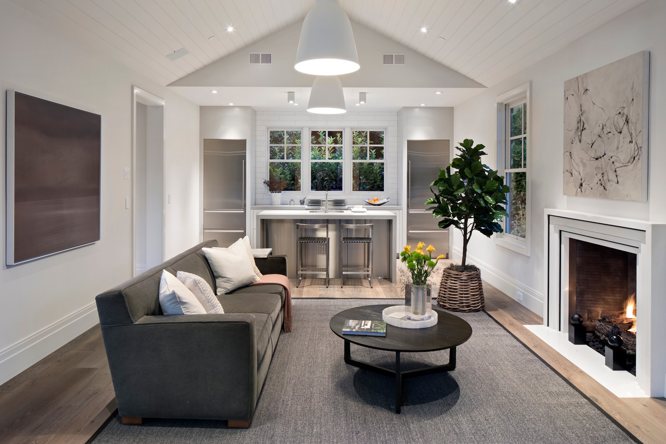 Living room of the guest house, with vaulted ceilings, fireplace, sofa and circular black table.