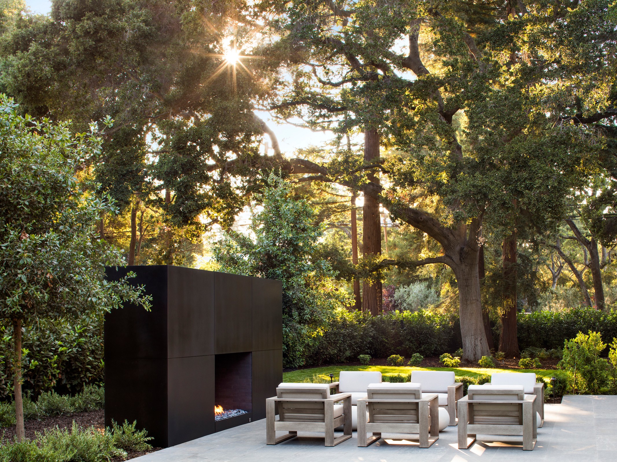 Outdoor living room patio with a black large fireplace and seating area