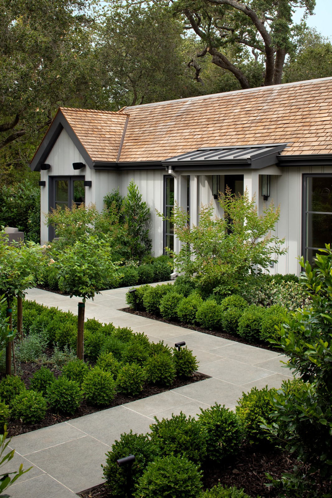 Walkway with green trees and plants, with an entranceway.