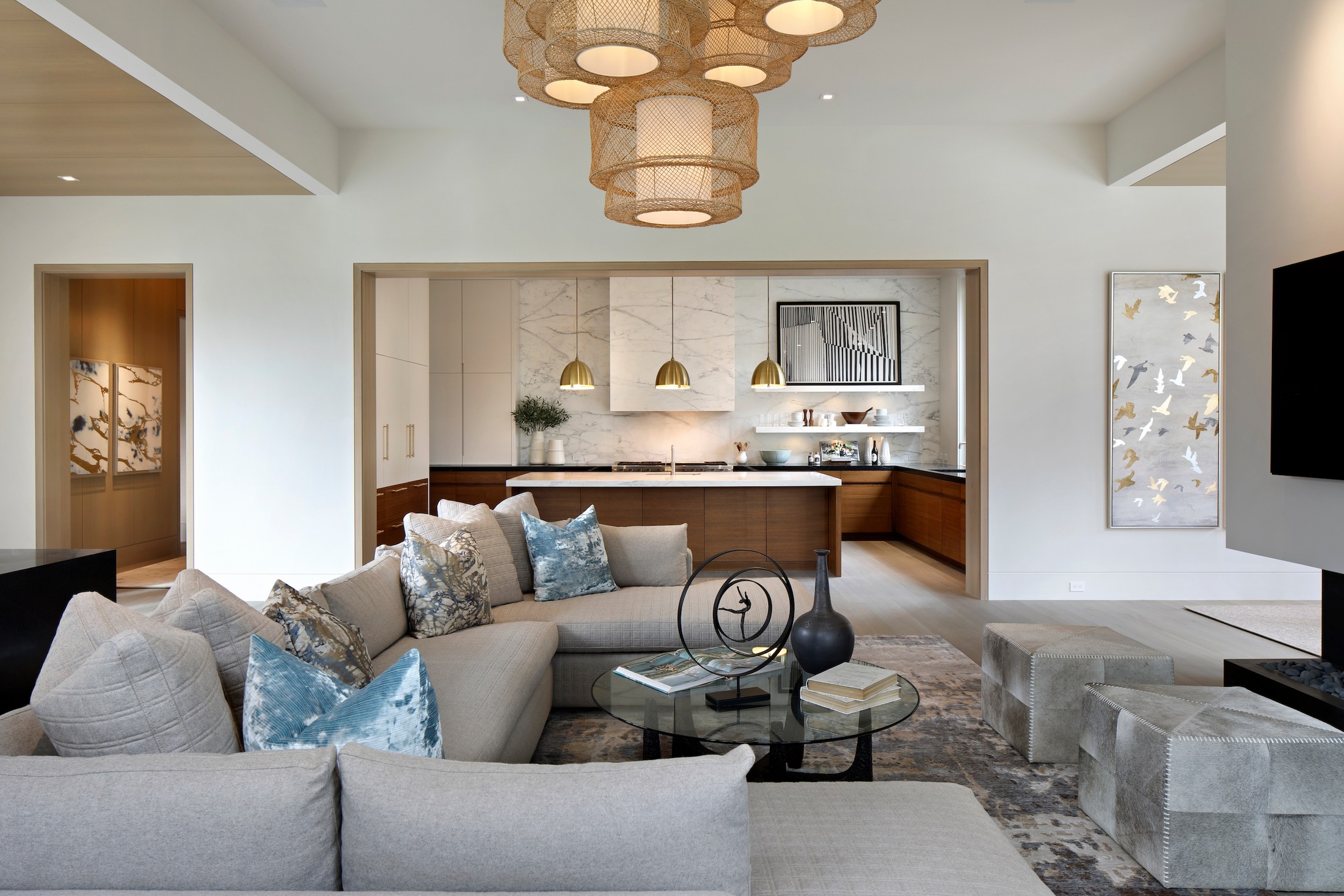 Family room with large couch, glass circular table. The kitchen is seen in the background.