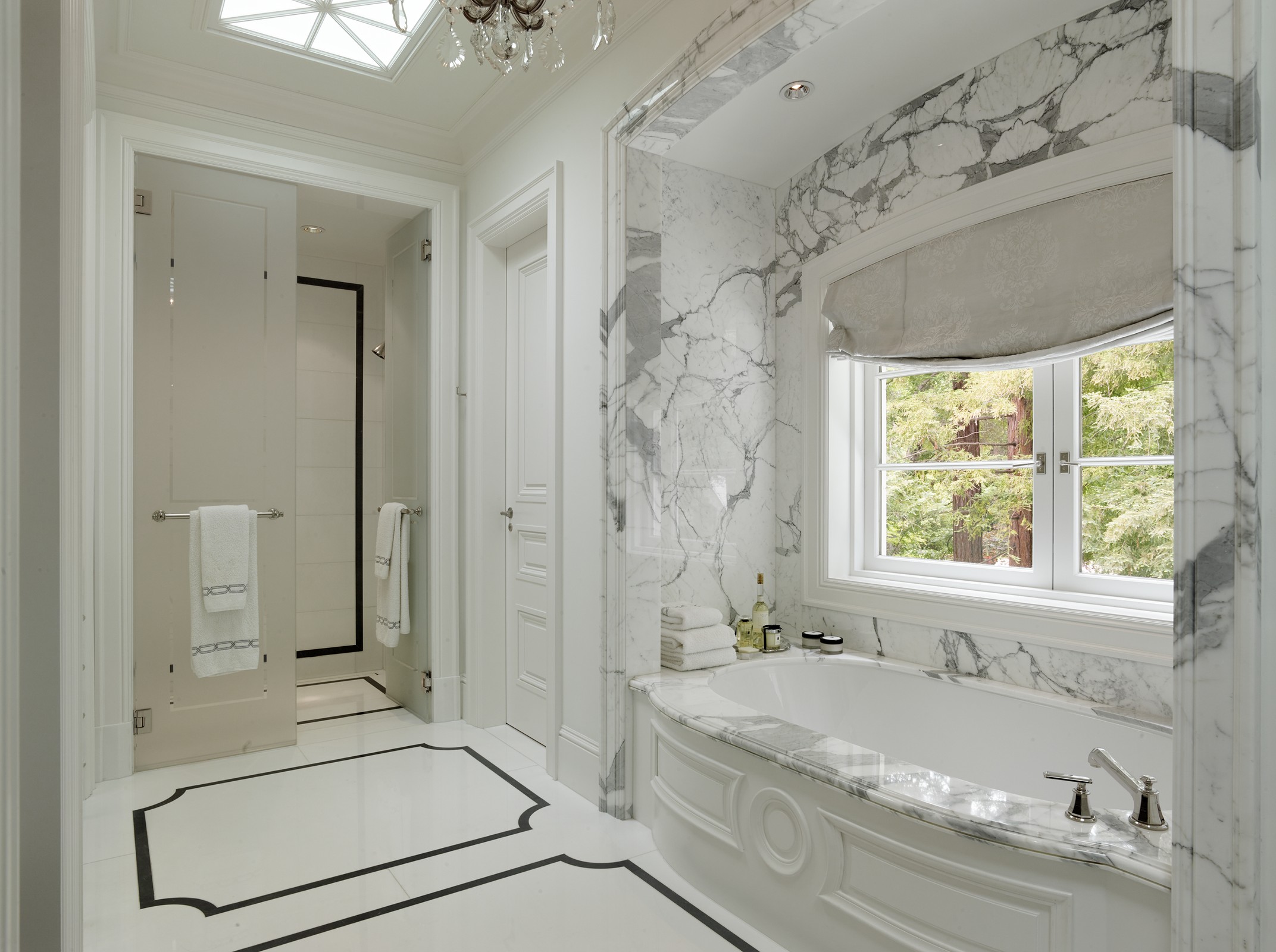 Bathroom which includes a tub with marble detailing and a shower