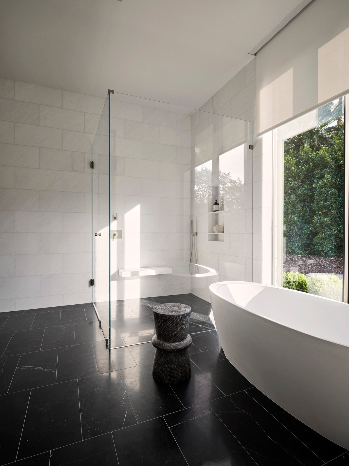 Bathroom with black tile floors, white tub, and glass shower.