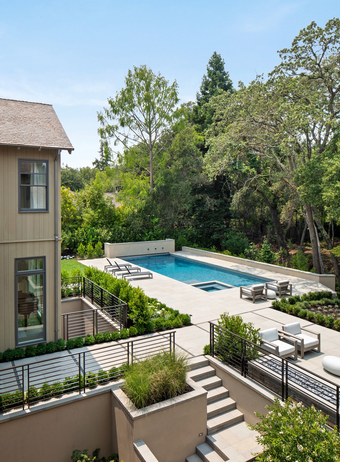 Image of the backyard, which has a pool and lounge chairs, surrounded by trees.