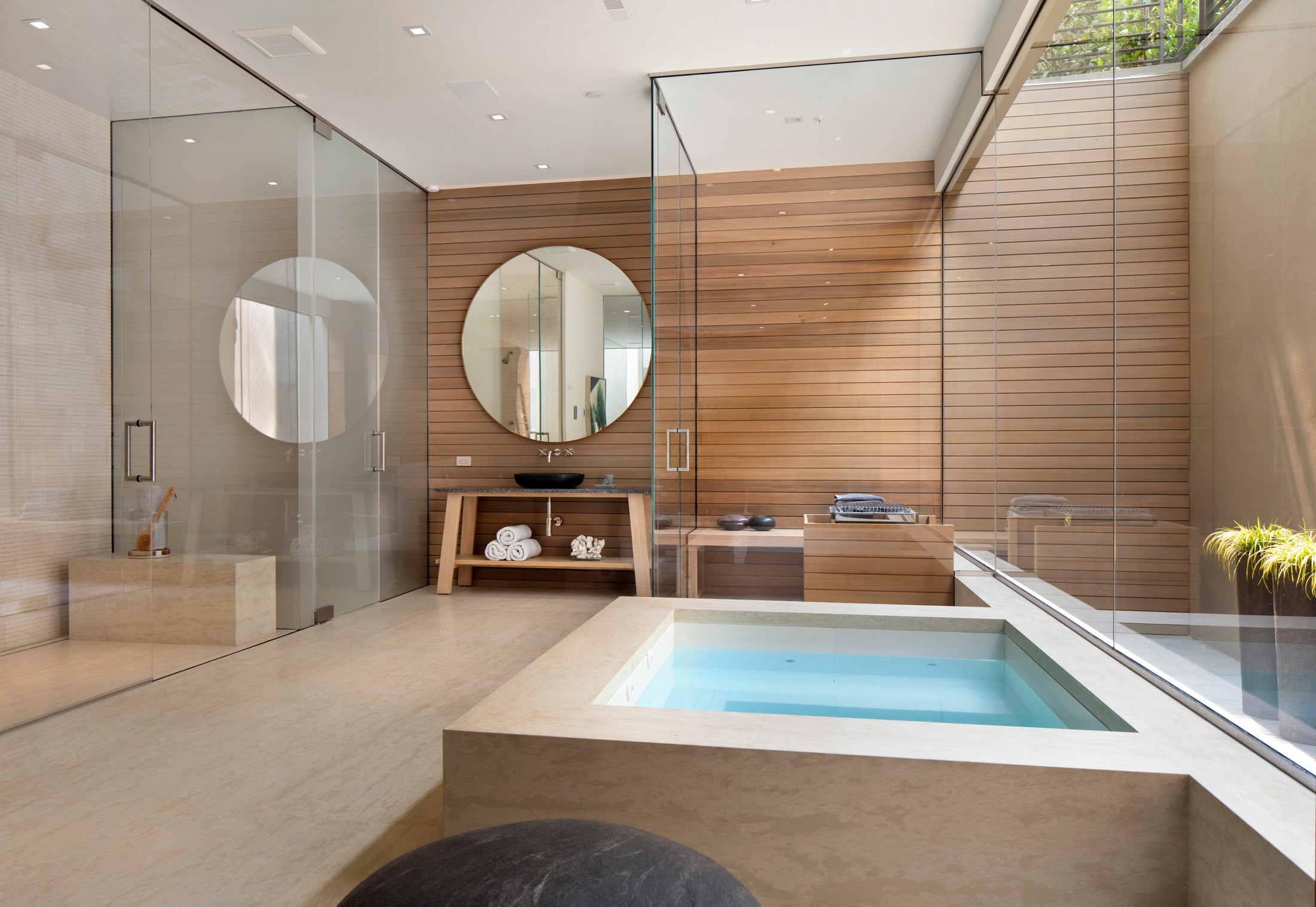 Spa which includes a rectangular bath, glass shower and large circular mirror
