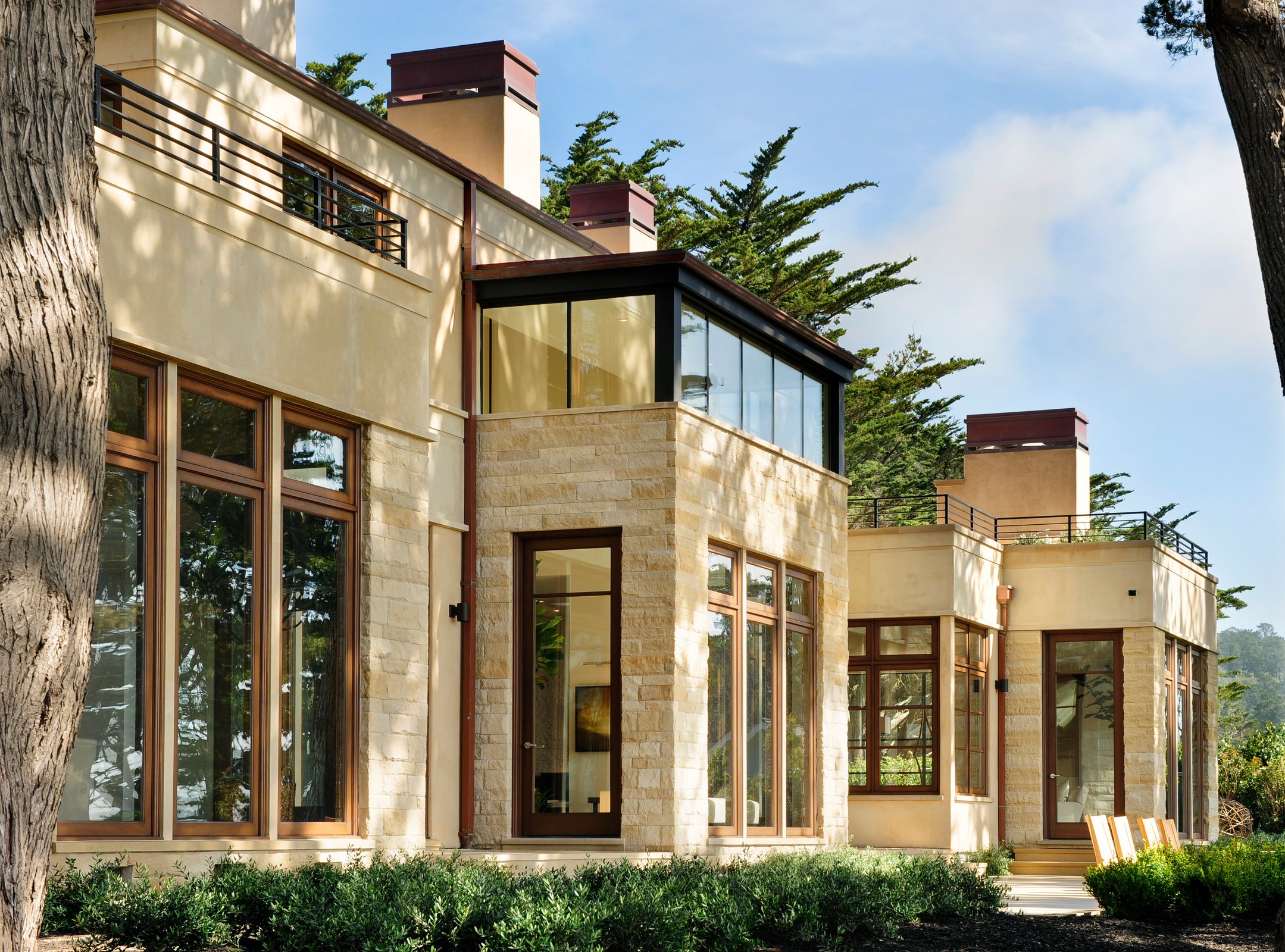 Exterior image of the home, which is made of light brick. There are black detailing on the windows and patio railings.