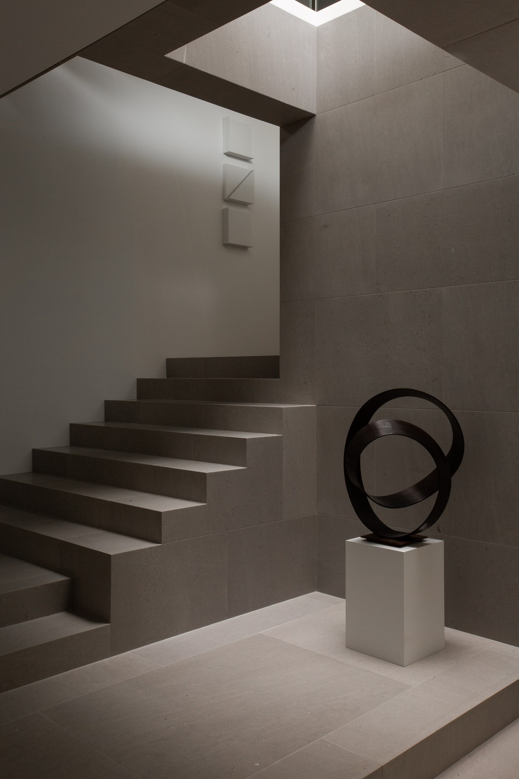 Stairway area with a large circular piece of artwork on a stand.