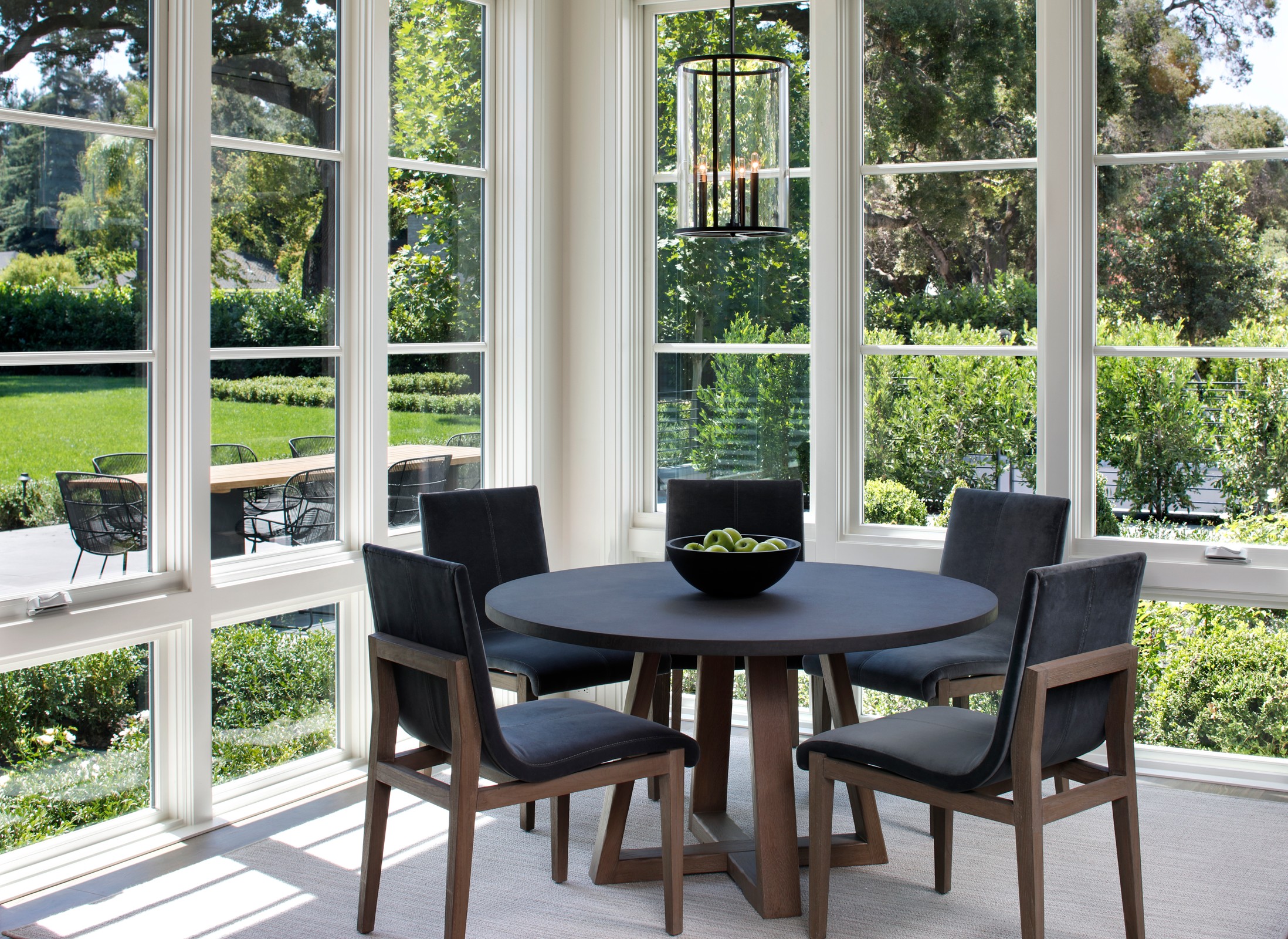 Kitchen nook with black and wood chairs and circular table.
