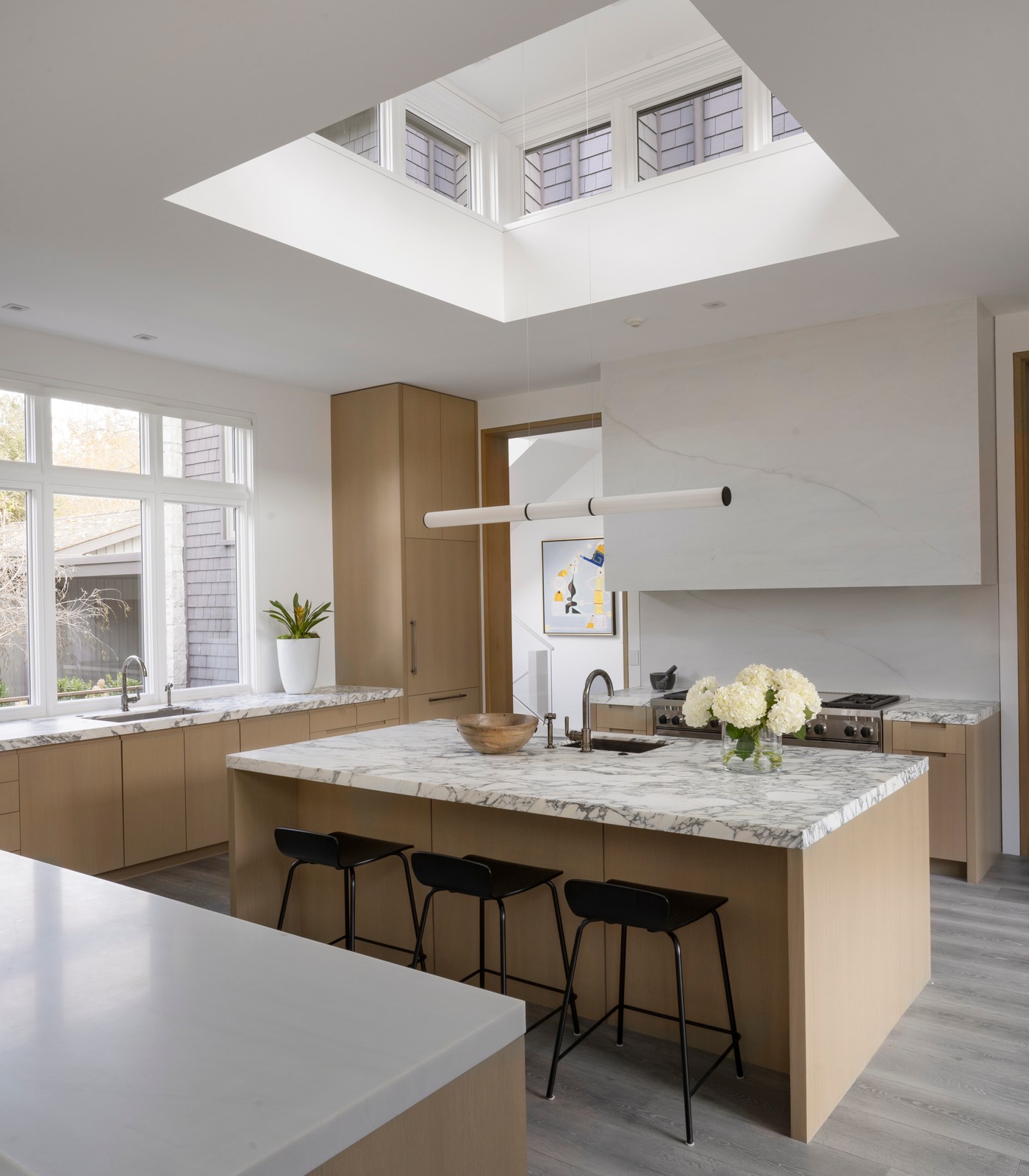 Kitchen with marble and wood detailing, with a large sunroof.