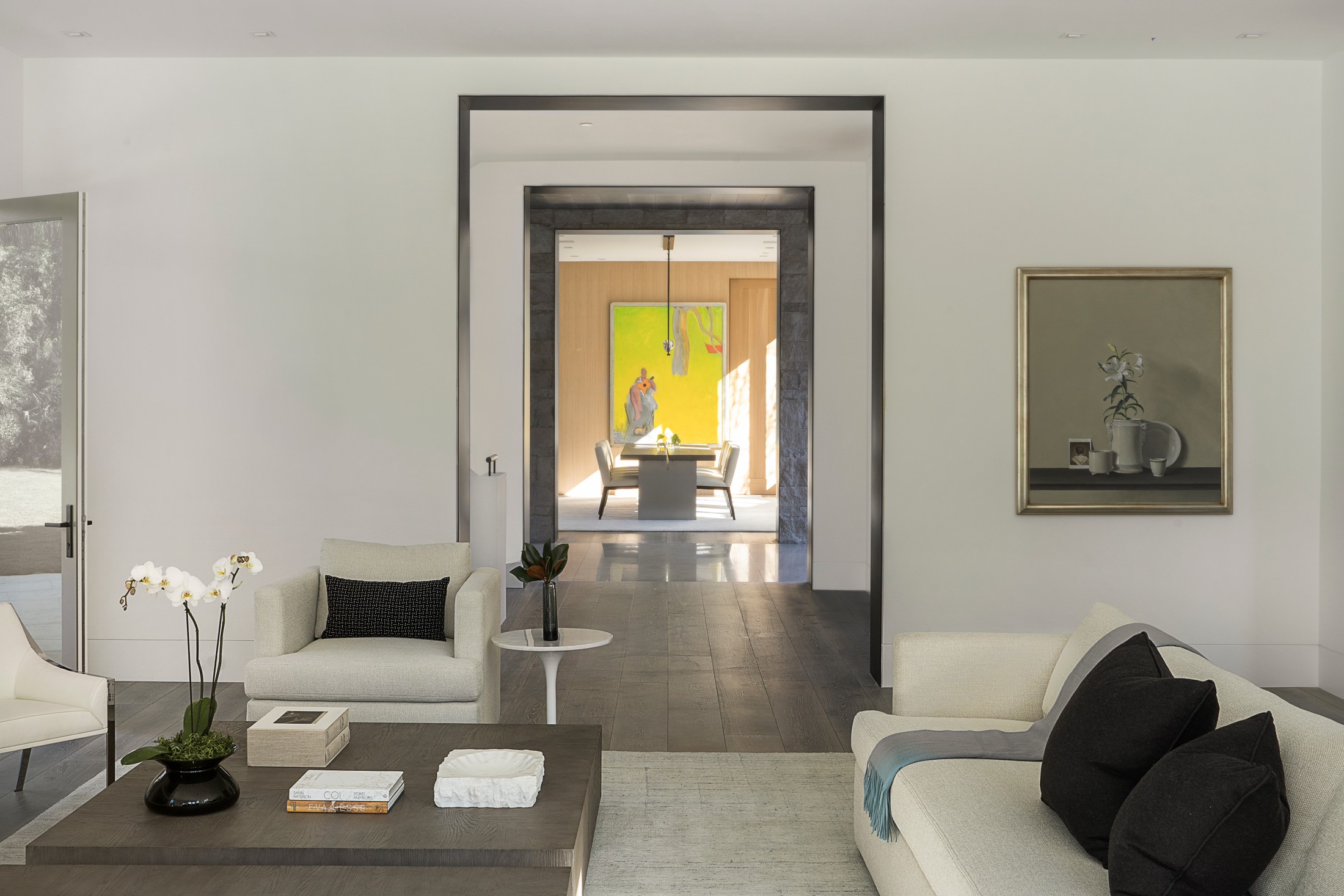 Seating area with sofa, seating, and artwork on the wall. the hallway shows the dining room area.